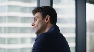 Şehir planında ciddi bir ofis penceresi var. Düşünceli iş adamı, modern kurumsal çalışma alanında duran yaratıcı çözümler üzerinde kafa yoruyor. Ticaret merkezinde zarif bir CEO düşüncesi..