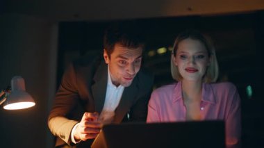 İş arkadaşları, gece ofis kapanışında başarılı bir başlangıç dizüstü bilgisayar aramasını tartışıyor. Gece geç saatlerde takım çalışmasının keyfini çıkaran gülümseyen iki yönetici. Gülen meslektaşlar iyi mali sonuçtan memnun.