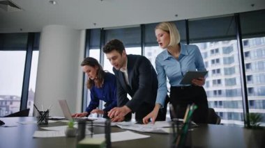 Ofis ekibi masa başında evrak işleriyle uğraşıyor. Profesyonel takım arkadaşları iş planlarını gözden geçiren şirket stratejilerini inceliyor. İş yerinde proje belgelerini okuyan üç yönetici.