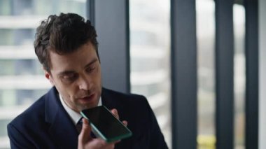 Ofis müdürü sesli mesaj kaydediyor. İş merkezi penceresi kapanıyor. Portre işadamı modern salonda sesli mesaj yazdırıyor. Ses tanıma uygulaması kullanan kendine güvenen girişimci.