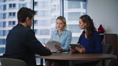 Emlak bürosunda müşteri alım sözleşmesi imzalıyor. Gülümseyen iş danışmanı iş kadınlarıyla el sıkışıyor ve anlaşma imzalıyor. Şirket ortakları başarılı bir pazarlıktan sonra el sıkışıyor.