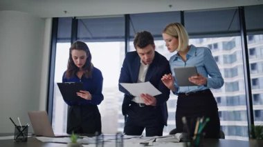 İş ortakları iş yeri yaratıcı ajansında etkileşim halindeler. Profesyonel yöneticiler kağıt tabletinde mali verileri tartışarak beyin fırtınası yapıyorlar. Üç meslektaşım birlikte pazarlama stratejisi üzerinde çalışıyor..