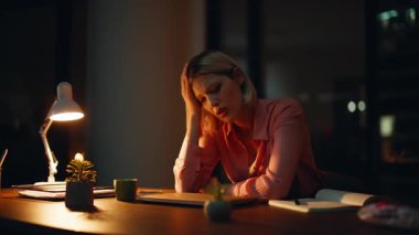 Çok çalışan serbest çalışan, gece yarısı iş yerinde oturan biri. Yakın plan. Stresli iş kadını, karanlık ofiste lamba ışığında patinaj çekiyor. Endişeli kadın yönetici işini kaybediyor. Kapalı alanda başarısız olmayı düşünüyor..