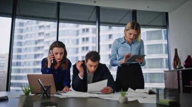 Ofis konferans odasında birden fazla iş arkadaşı çalışıyor. Çalışanlar cep telefonuyla konuşan kağıtları gözden geçirme projesinde çalışıyor. Aşırı yüklü şirket personeli evrak işleri ve beyin fırtınalarıyla meşgul.