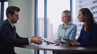 Finans şirketinde kendine güvenen yatırımcı güven ortaklığı sözleşmesi imzalıyor. Gülümseyen işadamı kadın danışmanlarla el sıkışıyor. CEO 'nun imza atması, iş yerinde yasal anlaşma yapması..