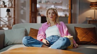 Sarışın bir kız uzaktan kumandayla kanal değiştiriyor ve en sevdiği televizyon programını buluyor. Evde televizyon izleyen sıkıcı bir kadın. Mutlu gevşemiş bayan kanepede ilginç bir diziyle hafta sonunun tadını çıkarın.