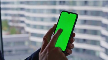 Patron internet uygulaması yeşil ekranlı cep telefonu panoramik pencerede duruyor. Kendine güvenen iş adamı kroma anahtar cep telefonundan SMS okuyor. Zengin yönetici akıllı telefondan sosyal medyayı izliyor.
