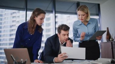 Şirket ekibi modern ofis çalışma alanının yakın çekimlerinde gazete okuyor. Üç takım arkadaşı pazarlama stratejisini tartışıyor ve verileri bilgisayara giriyorlar. İş projesinde birlikte çalışan grup arkadaşları.