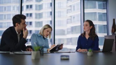 Kendine güvenen yönetici modern çalışma alanında birlikte oturan ofis arkadaşlarına projeyi açıklıyor. Gülümseyen iş ortakları el çırpıyor. Mutlu iş arkadaşları yatırım stratejisi sunumunu tatmin etti.