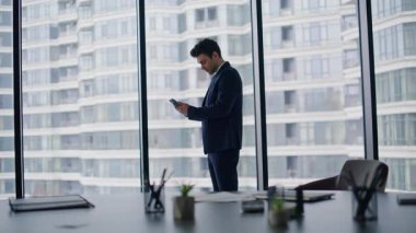 Ofis panoramik penceresinin yanında duran sinirli yönetici cep telefonu uyarısı. Endişeli iş adamı cep telefonu mesajını okuyor. Akıllı telefondaki kötü haber yüzünden endişeli girişimci şok oldu.