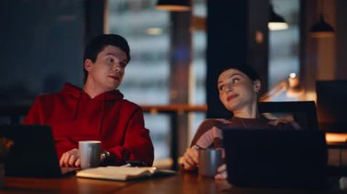 Koyu renk işyerinde kahve içen iki gece müdürü. Dost canlısı kadın, iş yerinde iş arkadaşı flörtü konuşuyor. Gülümseyen meslektaşlar iş yerinde dinlenmeyi çay yudumlamayı tartışıyorlar.