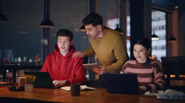 Ofis müdürü laptoplarda çalışan ekibi övüyor. Gülümseyen iki meslektaş başarılı bir takım çalışmasının tadını çıkarıyor. Profesyonel yönetici, iş arkadaşlarının çevrimiçi projesinden memnun.