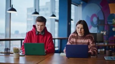 Modern çalışma alanında bilgisayarları daktilo eden dost canlısı iş arkadaşları. Gülümseyen kadın, çağdaş iş yerinde iş detaylarını konuşuyor. Bilgisayarda çalışan iki yönetici işbirliğinden keyif alıyor.