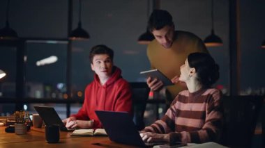 Karanlık şirket ofisindeki dizüstü bilgisayarlarda çalışan yönetici denetleme ekibi. Profesyonel CEO elinde tabletle genç iki öğrenciyle konuşuyor. Şirket ekibi gece projesinde işbirliği yapıyor..