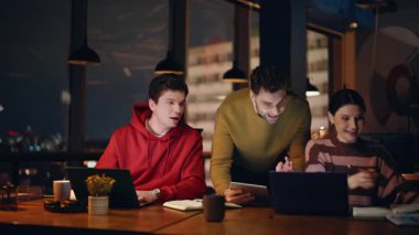 Gülümseyen çalışanlar karanlık çalışma alanının yakın çekiminde yeni başlayanları tartışıyor. Arkadaş canlısı ekip üyeleri proje üzerinde birlikte çalışıyorlar. Geceleri iş birliği yapan mutlu meslektaşlar..