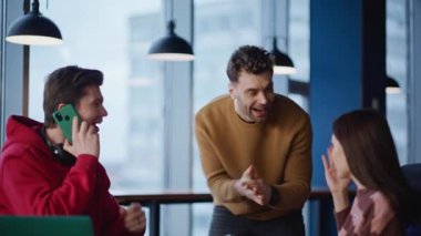 Modern ajans ofisindeki iş arkadaşlarını arayıp sevindirici haberler vermek. Mutlu ekip konuşmaları cep telefonuyla iş başarısının tadını çıkarın. Heyecanlı meslektaşlarım iş yerinde başarı duygusunu paylaşıyorlar..