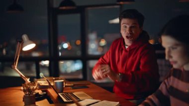 İnanılmaz iş arkadaşları, gece işyerinde beş sevindirici online zafer kazandılar. Duygusal iki yönetici el çırpıyor ve başlangıç başarısının keyfini çıkarıyorlar. Dizüstü bilgisayarlara bakan neşeli meslektaşlarımız mutluluğu hissediyorlar..