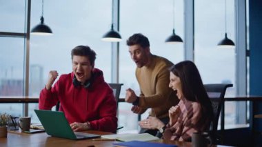 Ekip üyeleri ofis çalışma alanındaki başarıyı heyecanla bekliyor. Şirket işyerinde iş dünyasının zaferine sevinen çok mutlu meslektaşlar. Mutlu kazananlar başarılı bir başlangıç görünümlü dizüstü bilgisayarın keyfini çıkarıyorlar.