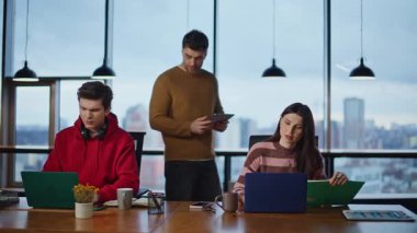 İşletme danışmanı iş arkadaşlarını kontrol ediyor. Bilgisayarlar açık alanda çalışıyor. İş arkadaşlarına yardım eden profesyonel bir iş adamı. Grup üyeleri yaratıcı başlangıç projesinde işbirliği yapıyor.