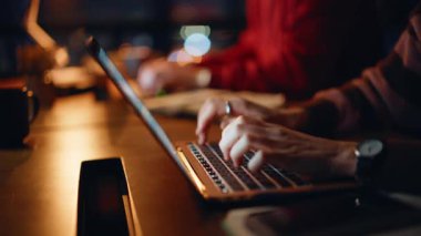 Karanlık ofis kapanışında dizüstü bilgisayar yazan çalışkan profesyoneller. Gece geç saatlerde bilgisayar başında çalışırken gülümseyen iki meslektaşım takım çalışmasının keyfini çıkarıyor. Gece işyerinde internet işiyle meşgul olan birkaç işkolik.