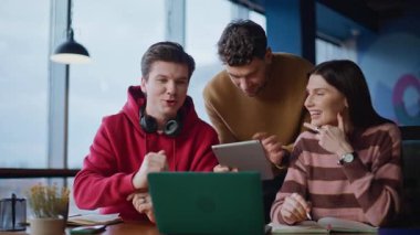 Çağdaş çalışma alanı kapanışında yaratıcı ekip birlikte çalışıyor. Gülümseyen grup yöneticileri laptoptan bahsederken takım çalışmasının keyfini çıkarıyorlar. Neşeli meslektaşlar birlikte çalışma alanındaki iş fikirlerini tartışıyor.