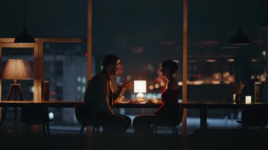 Gece lokantasında panoramik pencerenin yanında şehir manzaralı bir çift konuşuyor. Silüet romantik eşler karanlık kafede samimi iletişimden hoşlanırlar. Mutlu çift akşam randevusunu modern kafeteryada geçiriyor..