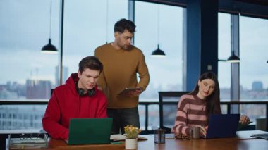 Ofis yöneticisi görünümlü stajyerler modern kurumsal çalışma alanında çalışırlar. İki arkadaş canlısı stajyer iş yerinde el sıkışıyor. Gülümseyen meslektaşlar açık alanda dizüstü bilgisayar projesi planlıyorlar