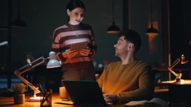Kadın patron, gece çalışma alanında gülümseyen adama tablet gösteriyor. Dost canlısı iş kadını fazla mesai yapan işçilere görevi açıklıyor. Mutlu meslektaşlar iş verilerini karanlık ofiste tartışır.