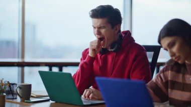 İş yerindeki dizüstü bilgisayarlarda sorunları çözen ciddi iş arkadaşları. Bilgisayarı kapatan genç bir kadın çalışma alanındaki çevrimiçi projeden bıktı. İki iş arkadaşı kapalı alanda nedensiz yere aşırı yüklendi..