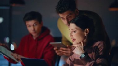 Profesyonel takım arkadaşları, tablet kapanışında dijital verileri kontrol ederek başlangıç aşamasında beyin fırtınası yapıyorlar. Takım arkadaşları karanlık ofisteki projede işbirliği yapıyor. Yaratıcı iş arkadaşları dizüstü bilgisayarları tartışıyorlar.