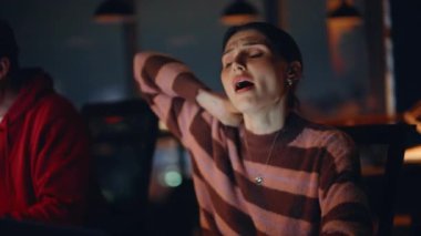 Karanlık şirket işyerindeki dizüstü bilgisayarlarda çalışan yorgun personel. Yorgun bir kadın kol saatini esnetiyor. Uykucu adam bilgisayarı kapatıyor ve geç saatlere kadar çalışmak istemiyor. Fazla mesai takım işbirliği.