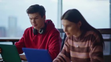 Kadın meslektaşım, adama online projesinde yardım ediyor modern şirket ofisinde birlikte oturuyorlar. Dizüstü bilgisayarlarda çalışan iki iş arkadaşı konuşuyor. Genç hippiler iş yerinde yaratıcı girişimi tartışıyor.