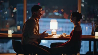 Gece kafeteryasında romantik bir yemekte konuşan mutlu siluet çifti. Gülümseyen kadın, kafenin bulanık manzarasında birlikte vakit geçirmekten zevk alıyor. Sevgili evli çift geceyi karanlık bir restoranda geçirir.