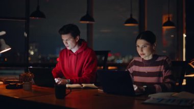 Gece müdürleri, karanlık şirket işyerindeki dizüstü bilgisayarlara uzaktan bakarak görevleri çözüyor. Bilgisayarda çalışan fazla mesai çalışanları. İki serbest çalışan birlikte çalışarak online araştırma yapıyor.