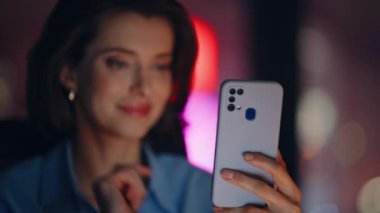 Akşamları iş yerinde akıllı telefon uygulamasına bakılıyor. Portre gülümseyen iş kadını cep telefonu uygulaması ile online alışveriş yapıyor. Neşeli kadın yönetici gece ofisinde telefon mesajı okuyor.
