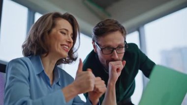 Mutlu ekip üyeleri başarılı bir proje olan dizüstü bilgisayarı ofiste yakından incelemekten memnuniyet duyuyorlar. Heyecanlı işletme yöneticileri el sıkışırken başarıların tadını çıkarırlar. Mutlu meslektaşlar duygusal tepki vererek harika haberler okuyorlar..