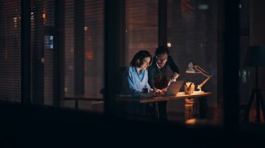 Profesyonel takım geç saatlere kadar ofis masasında dizüstü bilgisayar izliyor. Gece işyerinde iş stratejisi üzerinde çalışan iki iş arkadaşı. Şirket iş arkadaşları kapalı alanda pazarlama projesi planlıyor