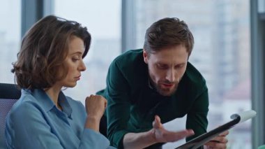 İş adamı ofis ışıklarının iç tarafındaki kadın çalışana belgeleri açıklıyor. Sakallı iş adamı iş kadınına iş verilerini gösteriyor. İş yerinde mali raporu tartışan iki meslektaş