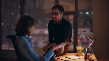 Karanlık şirket işyerinde laptopla dostça sohbet eden rahat personel. İki meslektaş, ellerinde kahve fincanları ile haberleri paylaşıyor. Sakin iş ortakları gece geç saatlerde iş fikirlerini tartışıyor