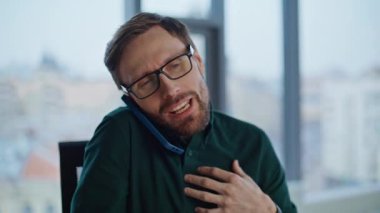 Başarılı bir lider ofis panoramik penceresinde cep telefonu pazarlığı yapıyor. Gülümseyen işadamı modern işyerindeki ortakları arıyor. Mutlu yönetici telefonla danışmanlık yapan bir müşteri ile görüşüyor..