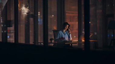 İş kadını, gece iş yerinde akıllı telefonla tartışıyor. Sinirli kadın yönetici, şehir ışıkları gören karanlık ofiste fazla mesai yapmaktan şikayet ediyor. Öfkeli yönetici kavgası.