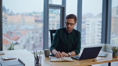 Ofis panoramik penceresinin yanında oturan şirket çalışanı deftere yazı yazıyor. Düşünceli iş adamı proje üzerinde çalışan fikirleri not alıyor. Sakallı yönetici iş planı üzerinde düşünüyor..