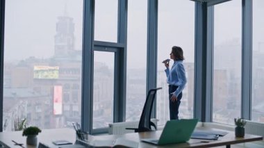 İşletme müdürü akıllı telefondaki sesli mesajları kaydediyor. Ofis panoramik penceresinin yanında duruyor. Cep telefonuyla sesli mesaj yazdıran zarif bir iş kadını. Ses tanıma uygulaması kullanan kendine güvenen bir bayan..