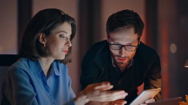 Ekip üyeleri, şirket işyerinde gece geç saatlerde iş projesi hazırlıyorlar. Yetenekli çalışanlar geceleri dizüstü bilgisayara bakarak fikir paylaşıyorlar. Başarılı finansal verileri tartışan iki mutlu iş arkadaşı.