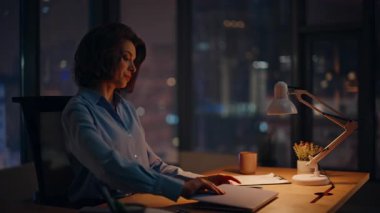 Serbest Çalışan, gece geç saatlerde modern iş yerinde dizüstü bilgisayar açıyor. Ciddi bir iş kadını karanlık ofiste panoramik pencereyle son teslim tarihine başlıyor. Gece işyerinde e-posta yazan zarif bir kadın..