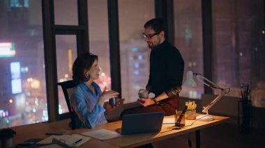 Ofis ekibi gece geç saatlerde iş yerinde kahve fincanlarını tokuşturuyor. İki gülümseyen meslektaşımız mesai molasından keyif alıyor. Mutlu iş kadını iş adamı birlikte içki içiyor..