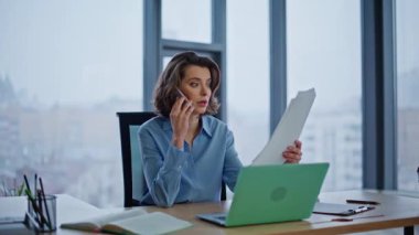 Yönetici cep telefonu oturarak rapor hatasını tartışıyor ve bilgisayarı kapatıyor. Tatminsiz iş kadını mali veri belgelerinden şikayetçi. Sinirli kadın CEO stresli akıllı telefon konuşmasını bitirdi..