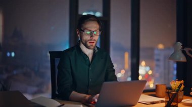 Profesyonel danışman, gece ofisindeki çağrıya cevap veriyor. Kapanış notları yazıyor. Fazla mesai çalışanı cep telefonu sohbetine başla. Çalışma masasında dizüstü bilgisayarla otur. Gözlüklü sakallı iş adamı telefonla konuşuyor..