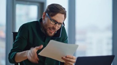 Öfkeli CEO akıllı telefon diye bağırıyor kağıtlar kırışıyor duygusal olarak. Cep telefonuyla iş belgelerini fırlatan öfkeli bir işadamı. Gözlüklü çılgın yönetici iflas çağrısı bitirdi..