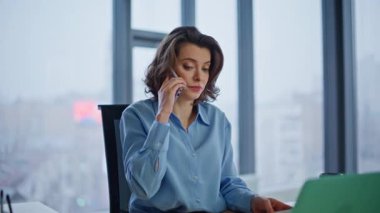 Ofis panoramik penceresinden cep telefonuyla endişelenen iş kadını tartışması. Sinirli lider cep telefonundan bağırıyor. Gazete atan stresli kadın akıllı telefon konuşmasını bitirdi..